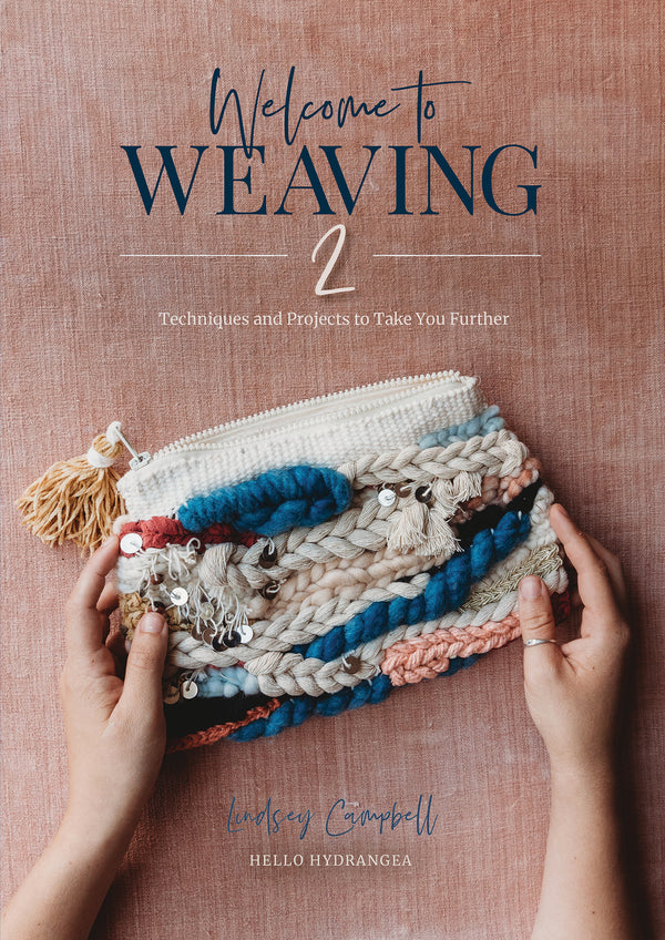 Two hands hold a textured, woven pouch with chunky yarn, tassels, and sequins against a pink fabric background. Text above reads, Welcome to Weaving 2: Techniques and Projects to Take You Further by Lindsey Campbell.