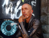 A bald man in a leather jacket sits thoughtfully before a graffiti wall and painted blue eye, evoking the vivid, surreal style of the Starman Tarot Remastered by Schiffer Publishing, Ltd., inspired by David Bowie.