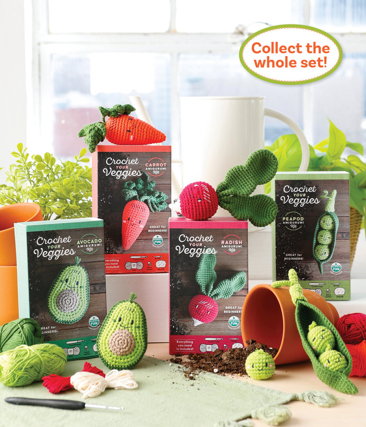 The Crochet Your Veggies Amigurumi Kit Radish by Schiffer Publishing, Ltd. is shown with crocheted veggies, yarn, hooks, a spilled plant pot, and a “Collect the whole set!” sign in the background.