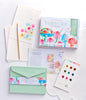 The Schiffer Publishing, Ltd. Watercolor the Easy Way Paint-Your-Own Watercolor Cards Garden kit includes a box, paint palette, brush, instructional booklet, floral notecards, and green envelope with vibrant mushroom and flower artwork displayed on a white surface.